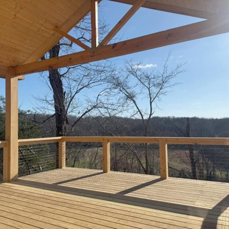 Custom covered wood deck with cable railing and vaulted roof overlooking a wooded Middle Tennessee property